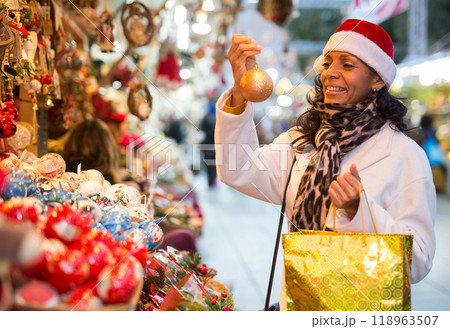 Positive woman selecting gifts at christmas fair Positive woman selecting gifts at christmas fair 118963507