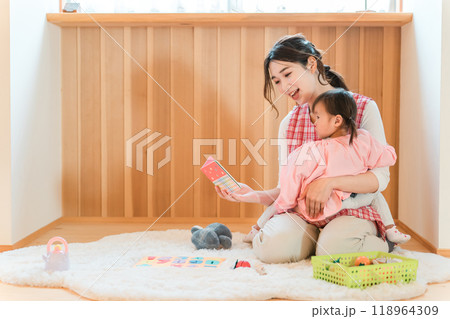 保育園・幼稚園・託児所・保育所で園児の女の子に絵本を読み聞かせする女性保育士・保母さん・シッター 保育園・幼稚園・託児所・保育所で園児の女の子に絵本を読み聞かせする女性保育士・保母さん・シッター 118964309