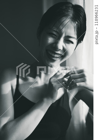窓辺で屈託のない無邪気な笑顔を見せる若い女性 窓辺で屈託のない無邪気な笑顔を見せる若い女性 118966231