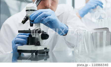 Young scientist or researcher in protective workwear studying new virus in microscope to develop antidote for fighting coronavirus Young scientist or researcher in protective workwear studying new virus in microscope to develop antidote for fighting coronavirus 118966340