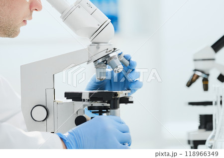 Scientist looks into a microscope near the laboratory, close-up Scientist looks into a microscope near the laboratory, close-up 118966349