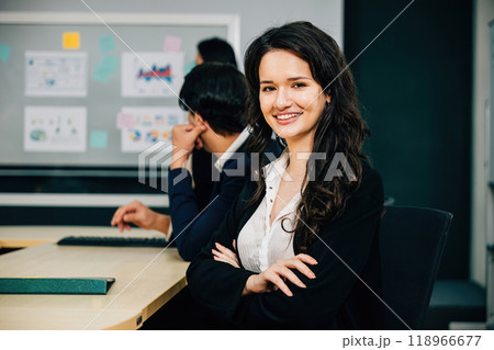 Within the meeting room, a businesswoman's portrait mirrors her expertise and leadership. The proud CEO, diverse colleague, and manager epitomize success through strategic teamwork and planning. 118966677