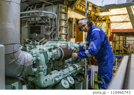 Marine Engineer in blue overall working in Engine room of ship. Work at sea. Motorman. Marine Engineer in blue overall working in Engine room of ship. Work at sea. Motorman. 118966743