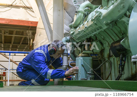 Marine Engineer in blue overall working in Engine room of ship. Work at sea. Motorman. 118966754