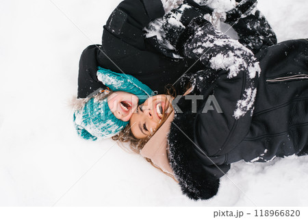 Woman and a child are laying in the snow. Mom is smiling and son is making a funny face. Scene is lighthearted and playful Woman and a child are laying in the snow. Mom is smiling and son is making a funny face. Scene is lighthearted and playful 118966820