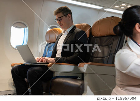 Business man using laptop in airplane during flight. Business traveler concept Business man using laptop in airplane during flight. Business traveler concept 118967004