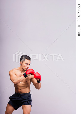 Confident male boxer in red gloves prepares for intense fight in studio Confident male boxer in red gloves prepares for intense fight in studio 118967094