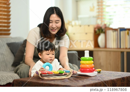 An adorable little boy and mother playing with colorful toys in a cozy living room An adorable little boy and mother playing with colorful toys in a cozy living room 118967808