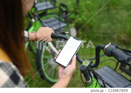 Woman renting electric bicycle through smart phone. Concept of technology and eco friendly transport concept 118967809