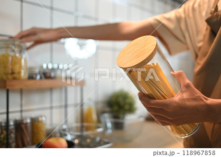 Close up image of man holding a glass jar filled with uncooked spaghetti. People, food and lifestyle concept 118967858
