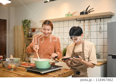 Young couple enjoying a lighthearted moment while preparing a meal together in kitchen 118967862