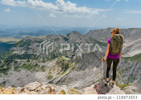 Woman Standing Backwards on Rocky Mountain Peak 118971653