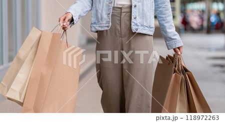 Stylish Shopper Holding Shopping Bags in Urban Setting for Black Friday Stylish Shopper Holding Shopping Bags in Urban Setting for Black Friday 118972263