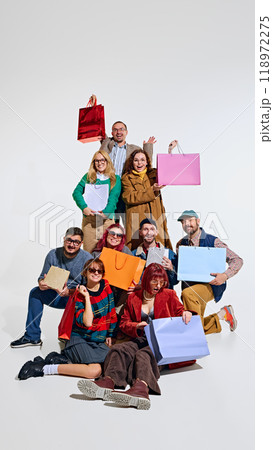 Crowd of people forming a human tower, showing their excitement about shopping, holding many colorful shopping bags 118972275