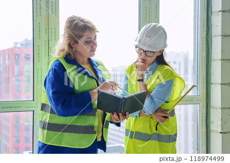 Two female industrial workers at construction site discussing work 118974499