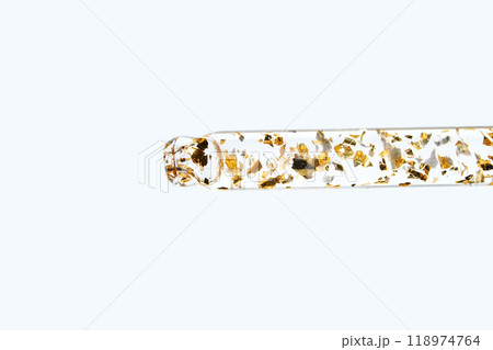 Transparent test tube with gold flakes on white background, modern minimalist Transparent test tube with gold flakes on white background, modern minimalist 118974764