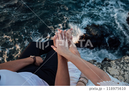 Hand of a man and a woman with wedding rings on a rock by the sea Hand of a man and a woman with wedding rings on a rock by the sea 118975610