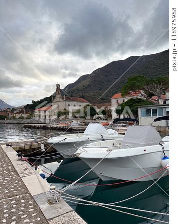 Boats docked at a peaceful marina with mountains and a historic church in the background. Quiet moment by the waterfront in autumn Boats docked at a peaceful marina with mountains and a historic church in the background. Quiet moment by the waterfront in autumn 118975988