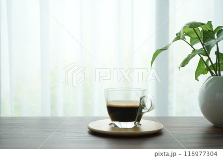 coffee glass cup and plants pot on wooden table with window view coffee glass cup and plants pot on wooden table with window view 118977304