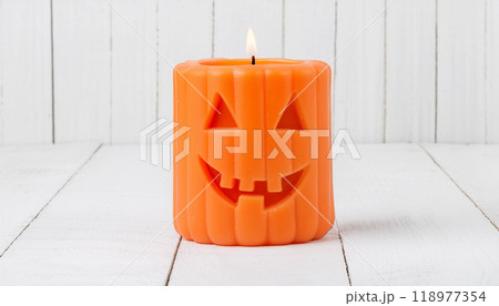 Jack-O'-Lantern Halloween Candle Lit on White Wooden Background for Festive Decor Jack-O'-Lantern Halloween Candle Lit on White Wooden Background for Festive Decor 118977354
