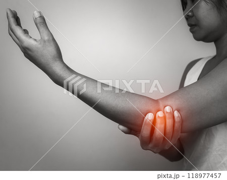 Woman with acute pain elbow with arm pain on gray background, Elbow and arm treatment, Female massaging her elbow muscle spasm, Healthcare and medical concept, Injuries and medical concept. 118977457