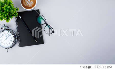 Top view white workspace office desk with office supplies. Flat lay work table with black notebook, Green leaf and coffee cup, Copy space for your advertising content. 118977468