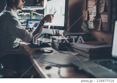 Analyzing data. Close-up of young businessman looking at monitor while sitting at the desk in creative office 118977518