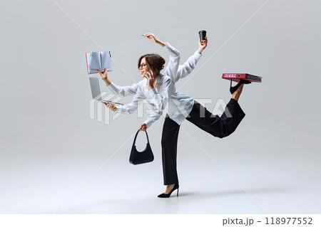 Woman in professional attire with multiple arms, managing laptop, phone, documents, and coffee. Master of multitasking. 118977552