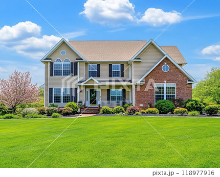 A beautiful home with a large front yard and blue sky in the background, representing the high-end residential real estate market of North America.  118977916