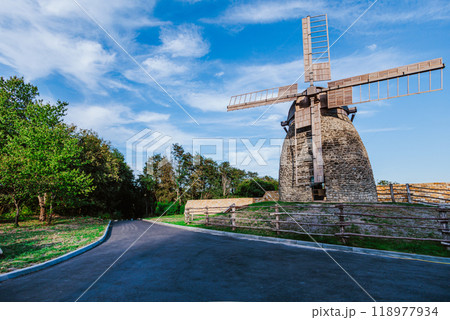 Stone windmill stands tall under a vibrant blue sky with scattered clouds. 118977934