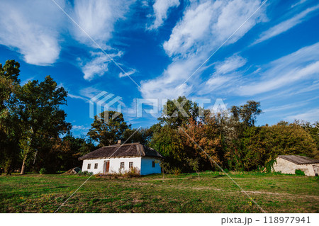 Traditional rural house with a thatched roof is nestled in a peaceful countryside Traditional rural house with a thatched roof is nestled in a peaceful countryside 118977941