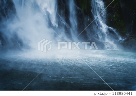Moody waterfall flowing in tropical rainforest at Milford Sound 118980441