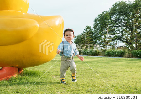 Asian toddler boy having fun on the grass at playground 118980581