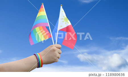 Cut out of hand holding both the LGBT flag and the Philippines flag, set against blue sky background with clipping paths. The symbolizing unity, diversity, and inclusion. 118980636