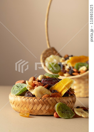 Dried tropical fruits, nuts and raisins on a beige background. 118981025