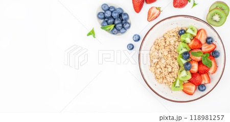 Oatmeal porridge with fruit and berries strawberry, kiwi, blueberry in bowl on white table, healthy breakfast Oatmeal porridge with fruit and berries strawberry, kiwi, blueberry in bowl on white table, healthy breakfast 118981257