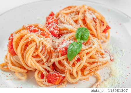 Spaghetti pasta with tomato sauce and fresh green basil on a white plate. Food recipe background. Close up 118981307