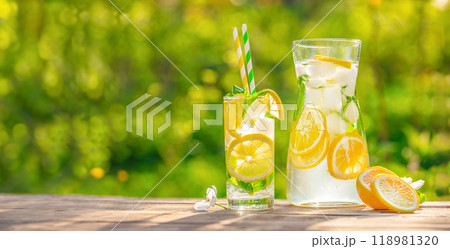 Summer refreshing lemonade drink cocktail with ice and lemon slices on the table in the garden. Organic cold refreshing lemonade drink 118981320