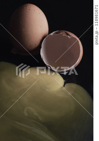 View of Broken egg yolk with Broken raw chicken eggshell in front of Fresh chicken egg (Hen eggs) on Dark background. View of Broken egg yolk with Broken raw chicken eggshell in front of Fresh chicken egg (Hen eggs) on Dark background. 118981671