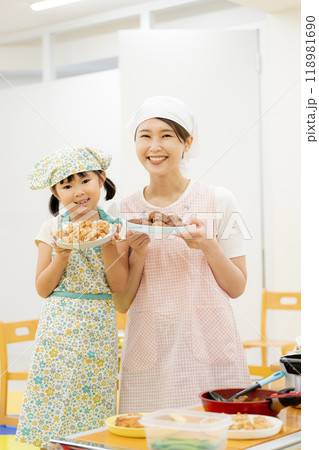 エプロンをして料理する母娘 118981690