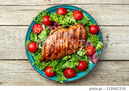 Grilled chicken breast ( fillet ) with lattuce salad and cherry tomatoes . Top view Grilled chicken breast ( fillet ) with lattuce salad and cherry tomatoes . Top view 118982316