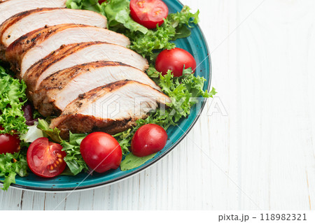 Grilled chicken breast ( fillet ) with lattuce salad and cherry tomatoes . Top view 118982321