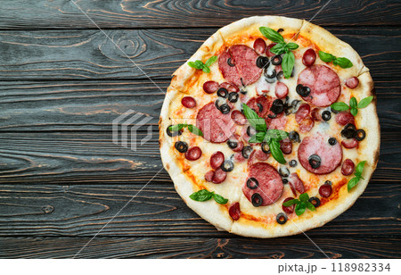 Pizza with mozzarella cheese , salami sausages , olives , and basil Pizza with mozzarella cheese , salami sausages , olives , and basil 118982334