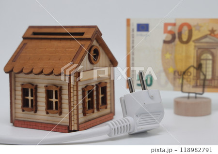 White electric cable and banknotes against the background of a toy model house 118982791