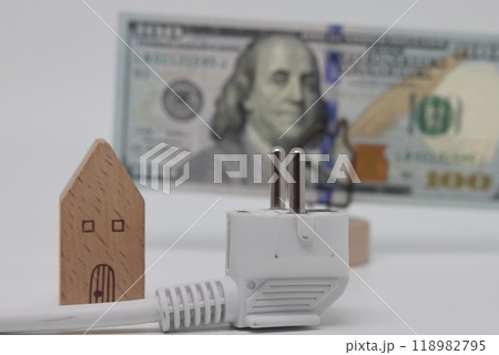 White electric cable and banknotes against the background of a toy model house 118982795