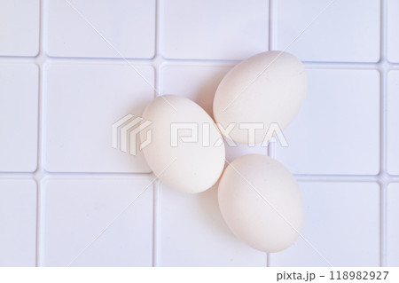 Three chicken bird eggs on a plastic checkered shelf in the fridge 118982927