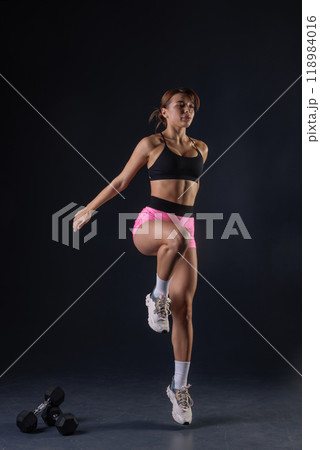 sporty girl doing exercises with dumbbells on black background, sport concept, healthy and beautiful body 118984016