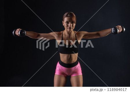 sporty girl doing exercises with dumbbells on black background, sport concept, healthy and beautiful body 118984017