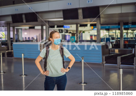 Woman in mask at empty airport at check in in coronavirus quarantine isolation, returning home, flight cancellation, pandemic infection worldwide spread, travel restrictions and border shutdown Woman in mask at empty airport at check in in coronavirus quarantine isolation, returning home, flight cancellation, pandemic infection worldwide spread, travel restrictions and border shutdown 118985860