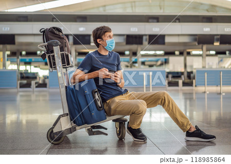 Man in mask at empty airport at check in in coronavirus quarantine isolation, returning home, flight cancellation, pandemic infection worldwide spread, travel restrictions and border shutdown 118985864